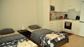 Une chambre d’hôtel de taille réduite, comprenant deux lits, une petite kitchenette et une salle de bain.