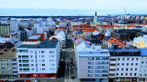 Un paysage urbain présentant une variété de bâtiments, dont un imposant bâtiment blanc orné d’une enseigne rouge sur laquelle on peut lire « Asia Market ».