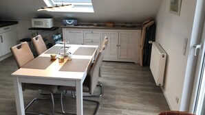 A compact kitchen with a dining table, chairs, a microwave, and a radiator.