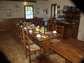 Un comedor con una mesa de madera dispuesta para el desayuno, incluyendo cruasanes y café.