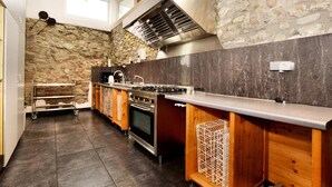 A kitchen with a stone wall, a gas stove, and a wooden cabinet. - La Ferme des Prés (Neuilly-en-Sancerre)