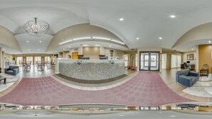 A spacious lobby with a reception desk, seating area, and a large chandelier.
