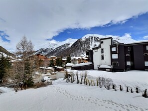 A snow-covered mountain town with modern buildings, a clear sky, and a visible road.