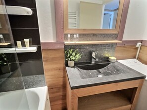 Ein Badezimmer mit einem schwarzen Waschbecken, einem hölzernen Waschtisch und einem Spiegel darüber.