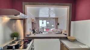 A kitchen with a stove, sink, and cabinets, a dining area with chairs, and a view of the street. - 2-room apartment mountain view - 4 guests (Val-d'Isère)