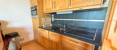 A kitchen with wooden cabinets, a black countertop, and a stainless steel sink.