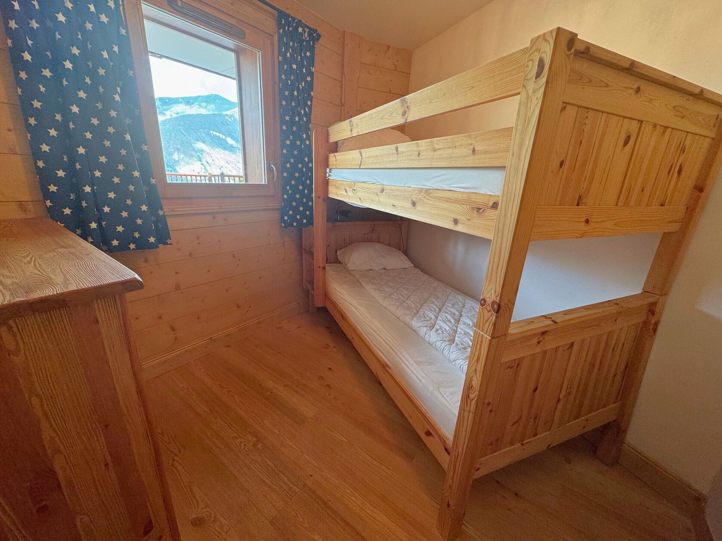 A wooden bunk bed room with a window and curtains.