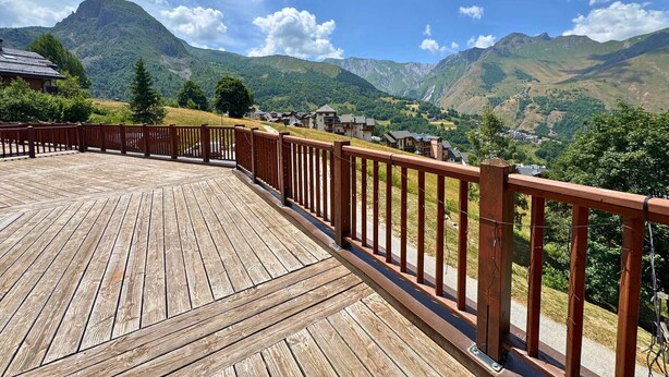 Una terrazza in legno con ringhiera che si affaccia su un paesaggio montuoso.