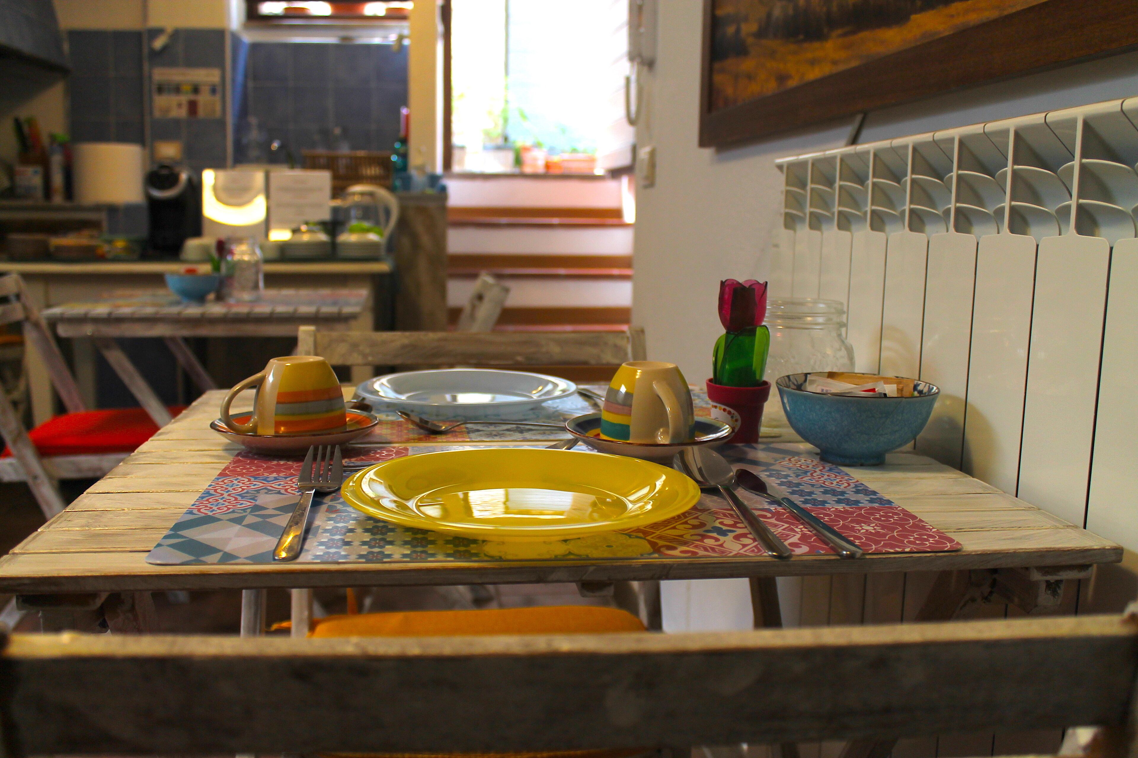 Una mesa de comedor con un plato amarillo, un tenedor y un cuchillo.