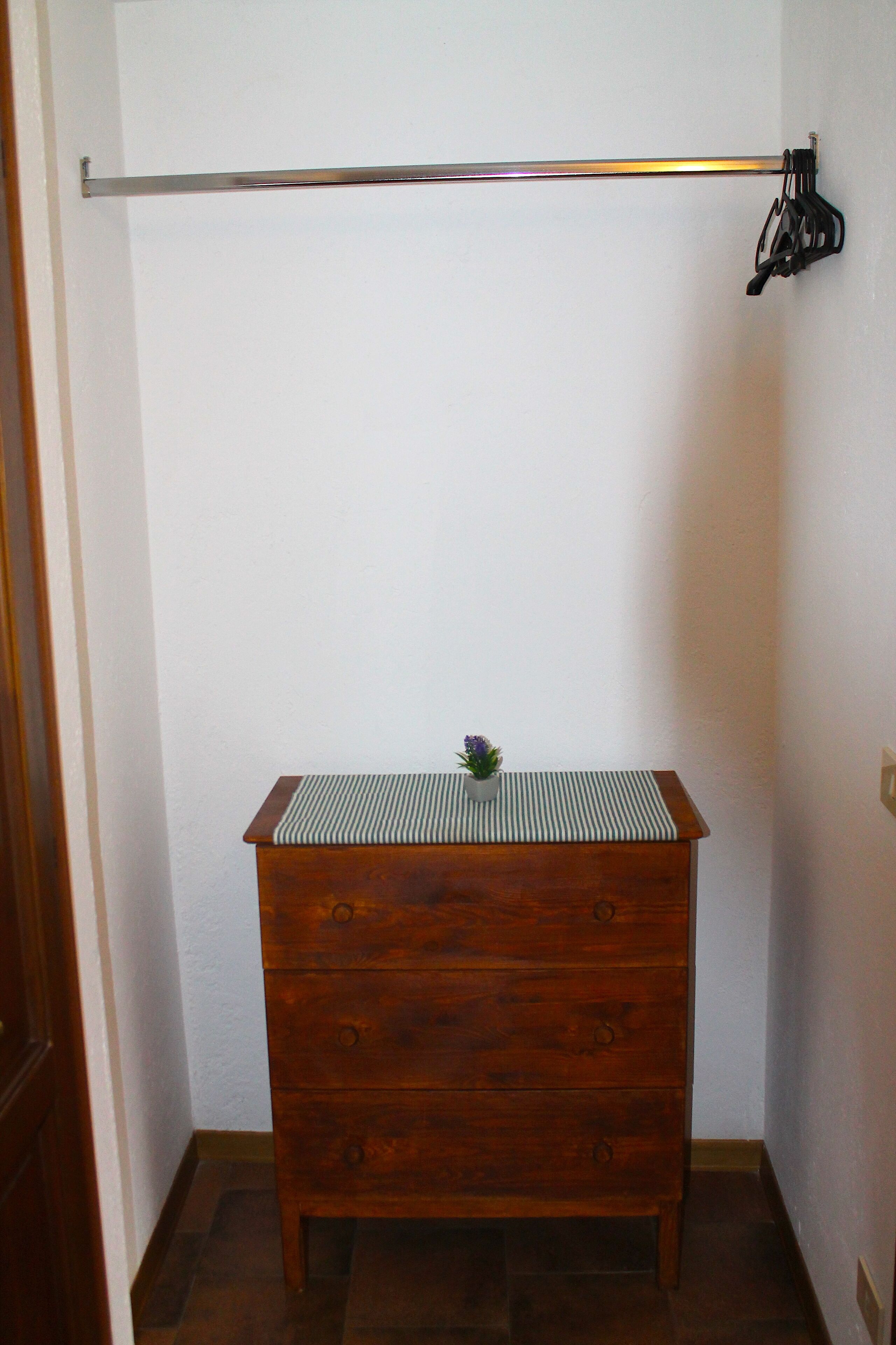 Ein Eckzimmer mit einem Holzkasten, einer Metallstange und einer kleinen Pflanze darauf.