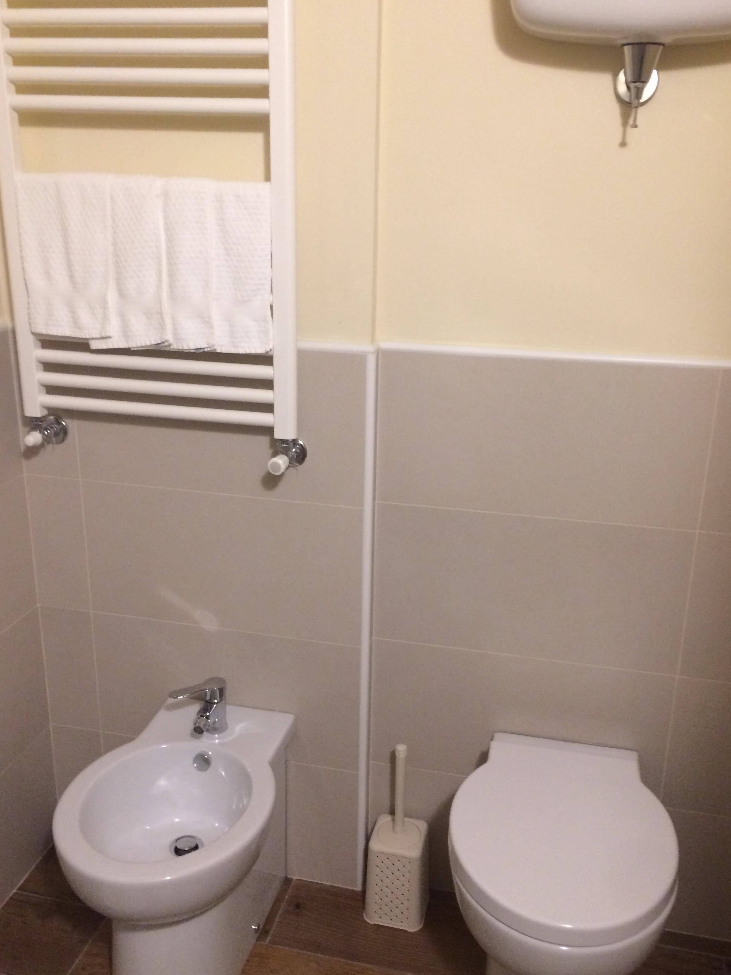 Un baño con bidé, inodoro, toallero y lavamanos empotrado.