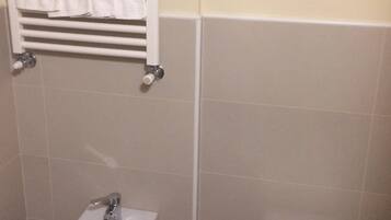 Un baño con bidé, inodoro, toallero y lavamanos empotrado.