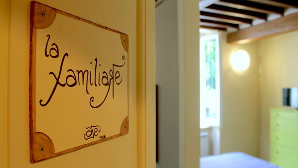 Une enseigne portant l’inscription « la Familiage » est fixée à un mur, indiquant qu’il s’agit d’un hébergement adapté aux familles.
