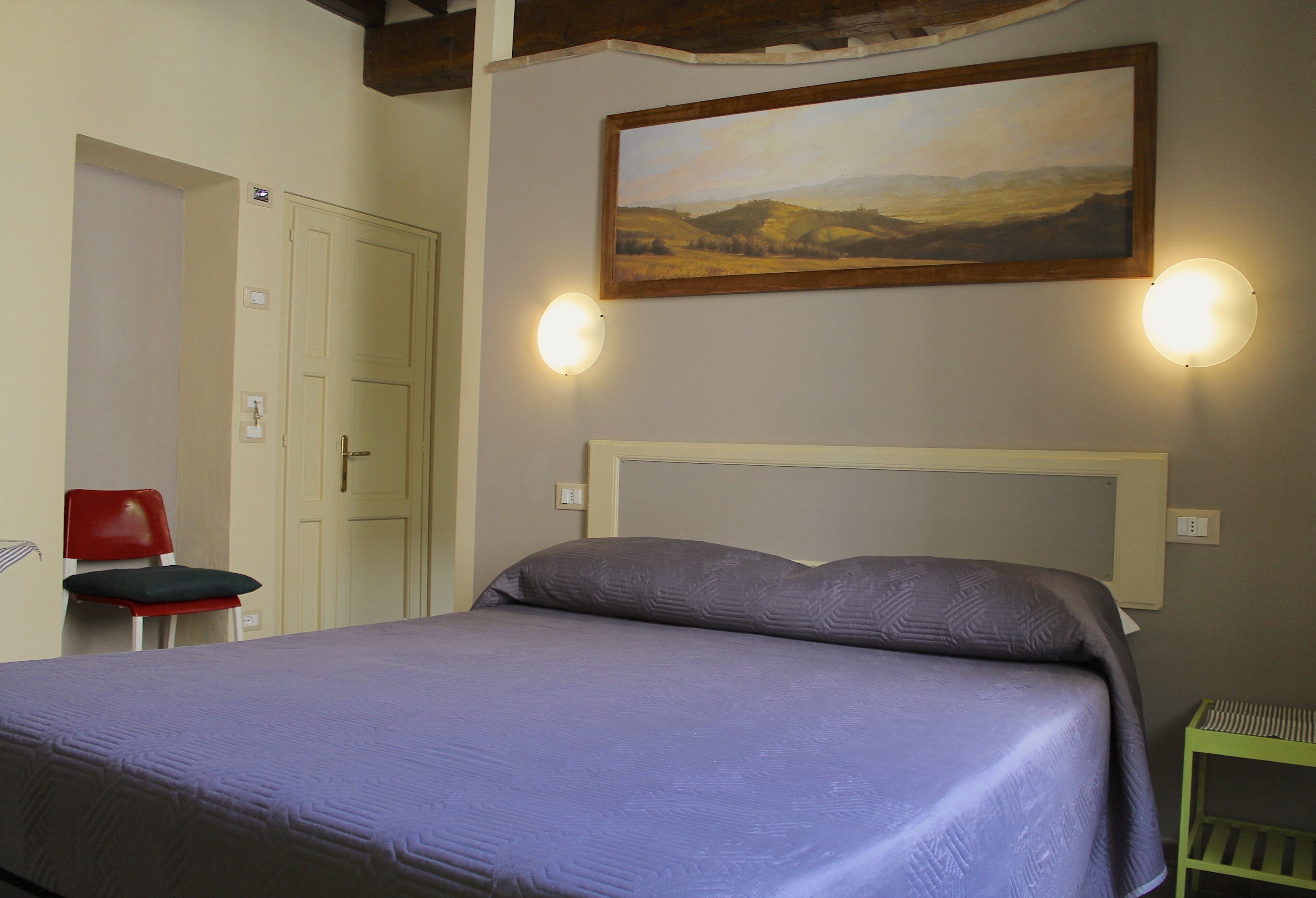Un dormitorio con cama, un cuadro en la pared y una silla.