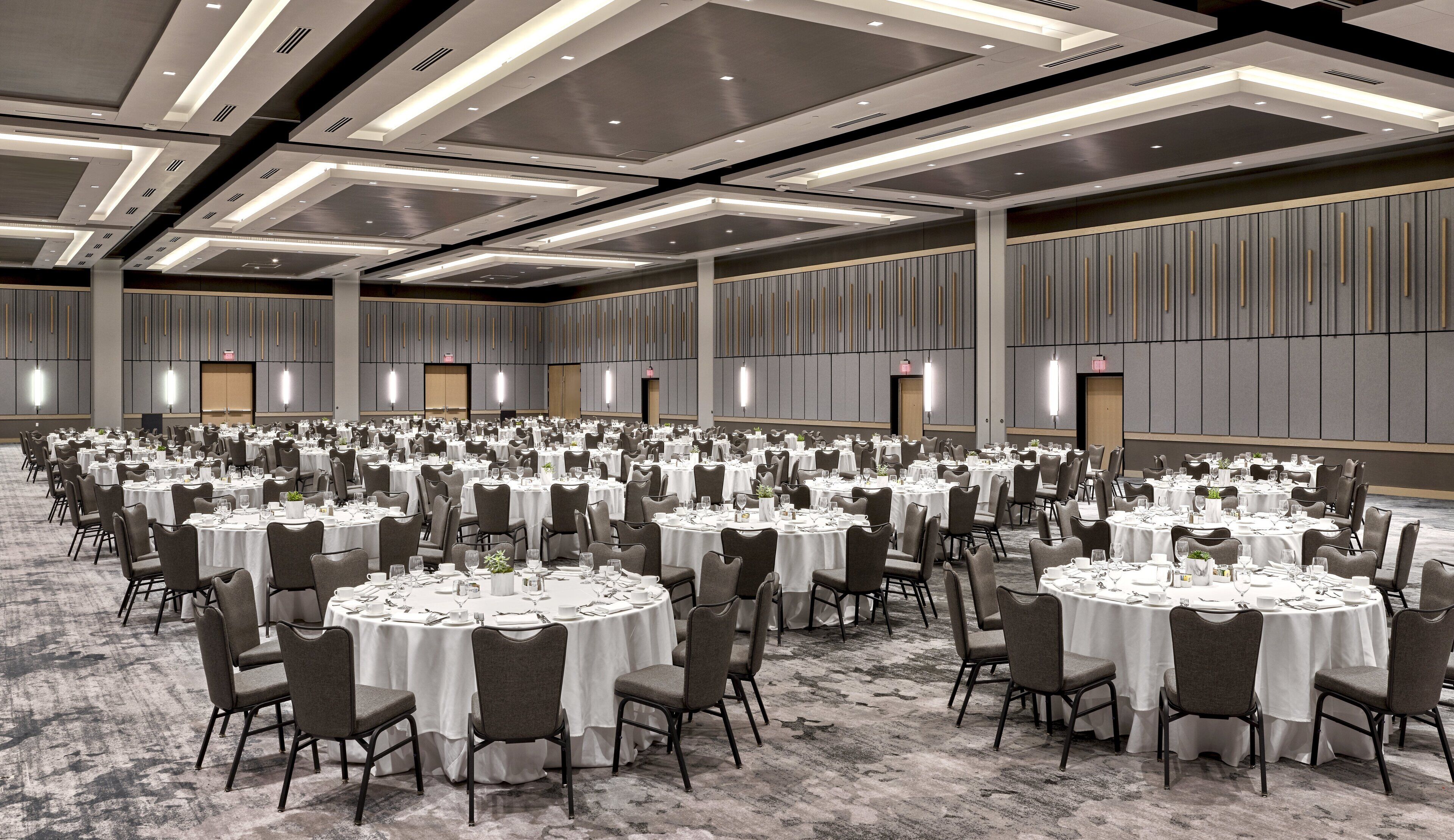 A large banquet hall with round tables set for dining, equipped with chairs and table settings.