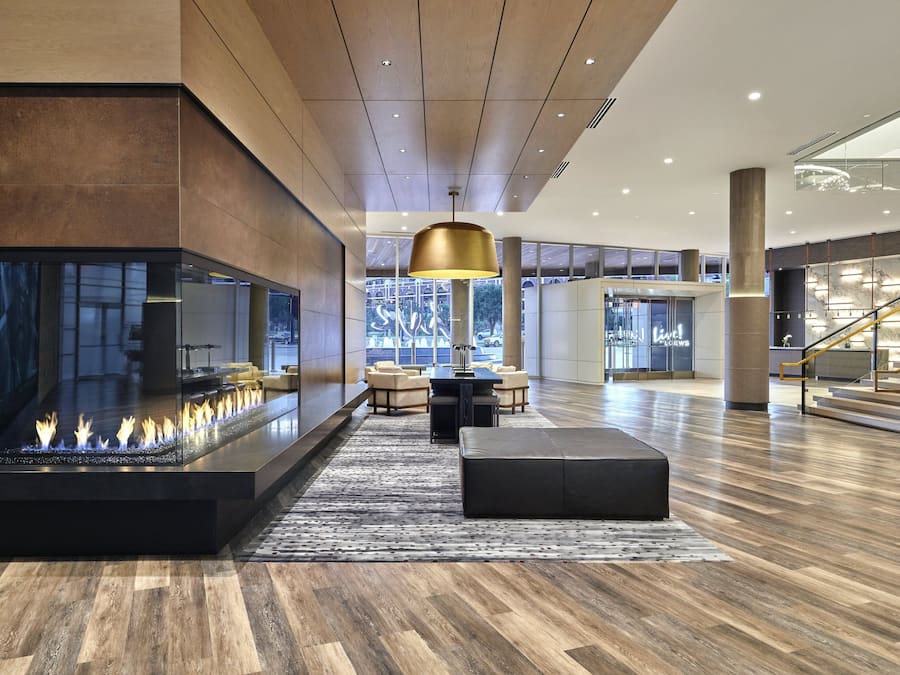 A modern lobby with a central fire feature, seating area, and a staircase.