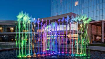 A nighttime view of a water fountain with colorful lights in front of a modern building.