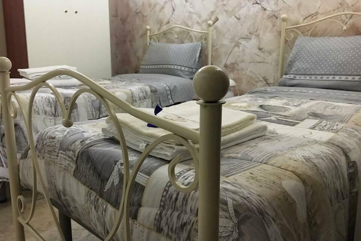 A bedroom with two beds, marble-patterned walls, and a metal bed frame.