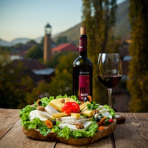 A wooden board with cheese, nuts, and vegetables, a bottle of Merlot wine, and a glass of wine. - Sheki Palace Hotel (Sheki)