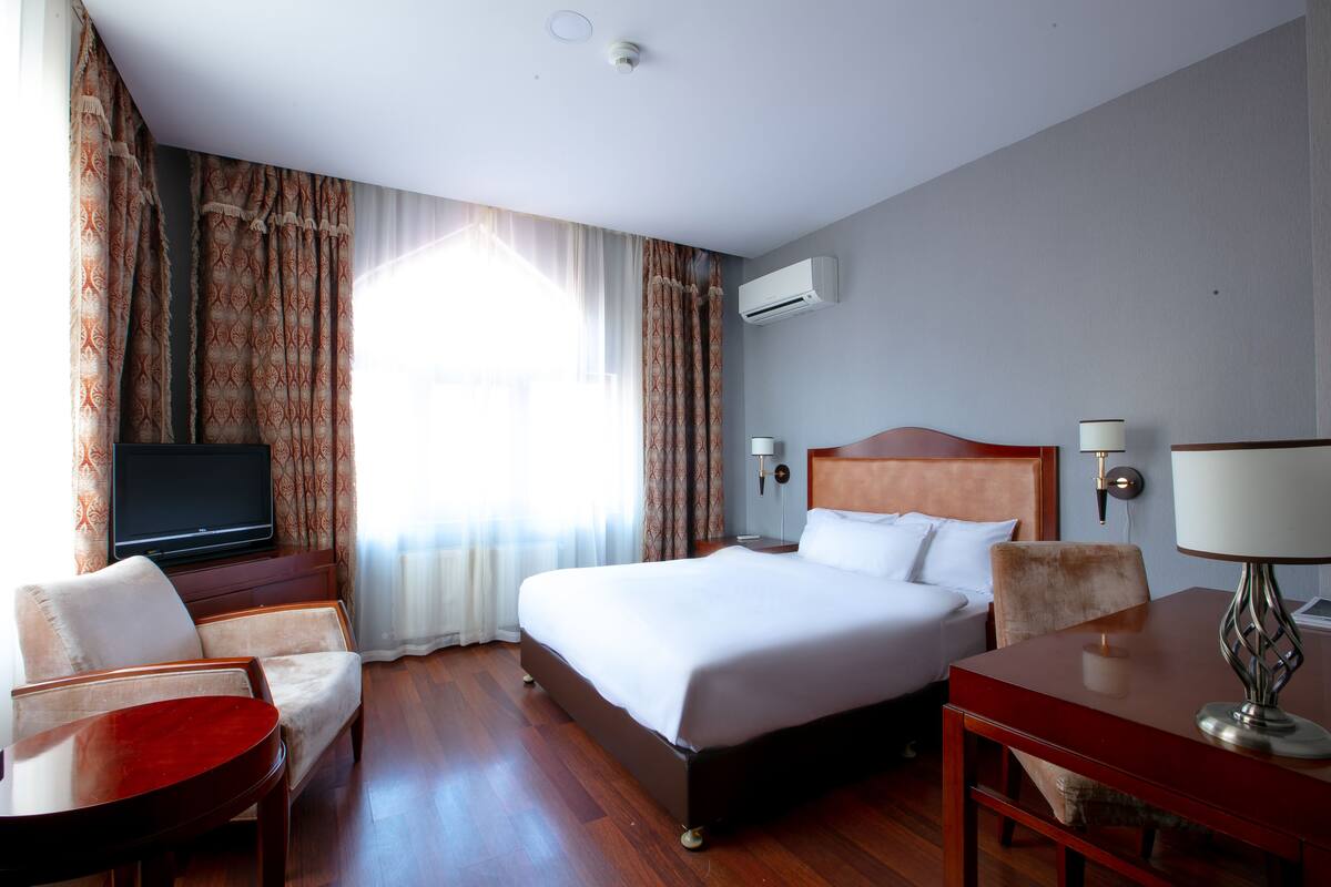 Une chambre d’hôtel équipée d’un lit, d’une télévision, d’un bureau, d’une chaise et d’une lampe.