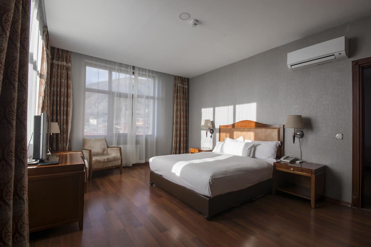 Une chambre d’hôtel avec un grand lit, un bureau, une chaise et une fenêtre avec des rideaux.
