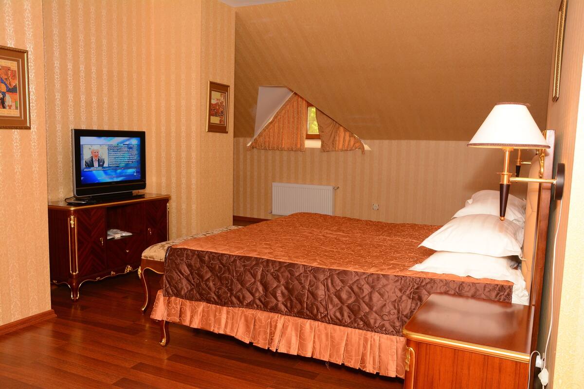 Une chambre d’hôtel avec un lit, une télévision, une table de chevet et une lampe.