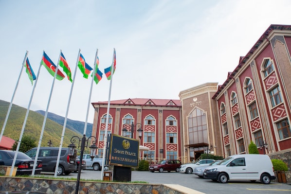 A building with a sign reading "Shari Palace Restaurant" and flags in front. - Sheki Palace Hotel (Sheki)
