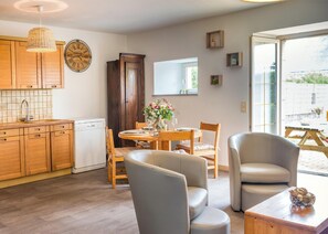 A modern kitchen with wooden cabinets, a dining area with a table and chairs, and a large window providing natural light.