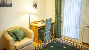 A cozy room with a sofa, a desk, a lamp, and a patterned rug. - NATURION Hotel Hinterzarten (Hinterzarten)