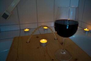 Uma mesa de madeira com uma taça de vinho e velas.