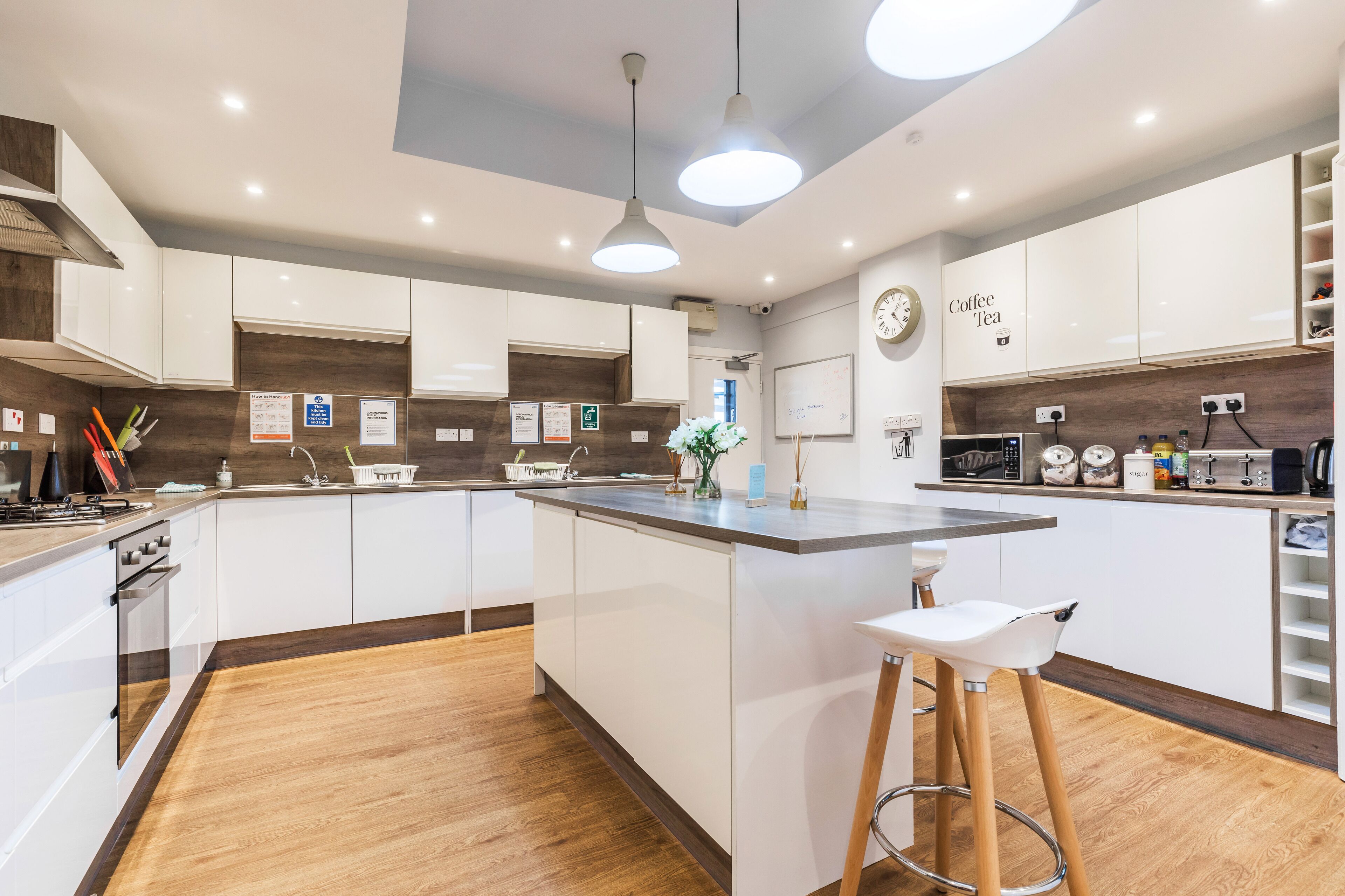 A modern kitchen with white cabinets, a wooden countertop, and a built-in island with stools.