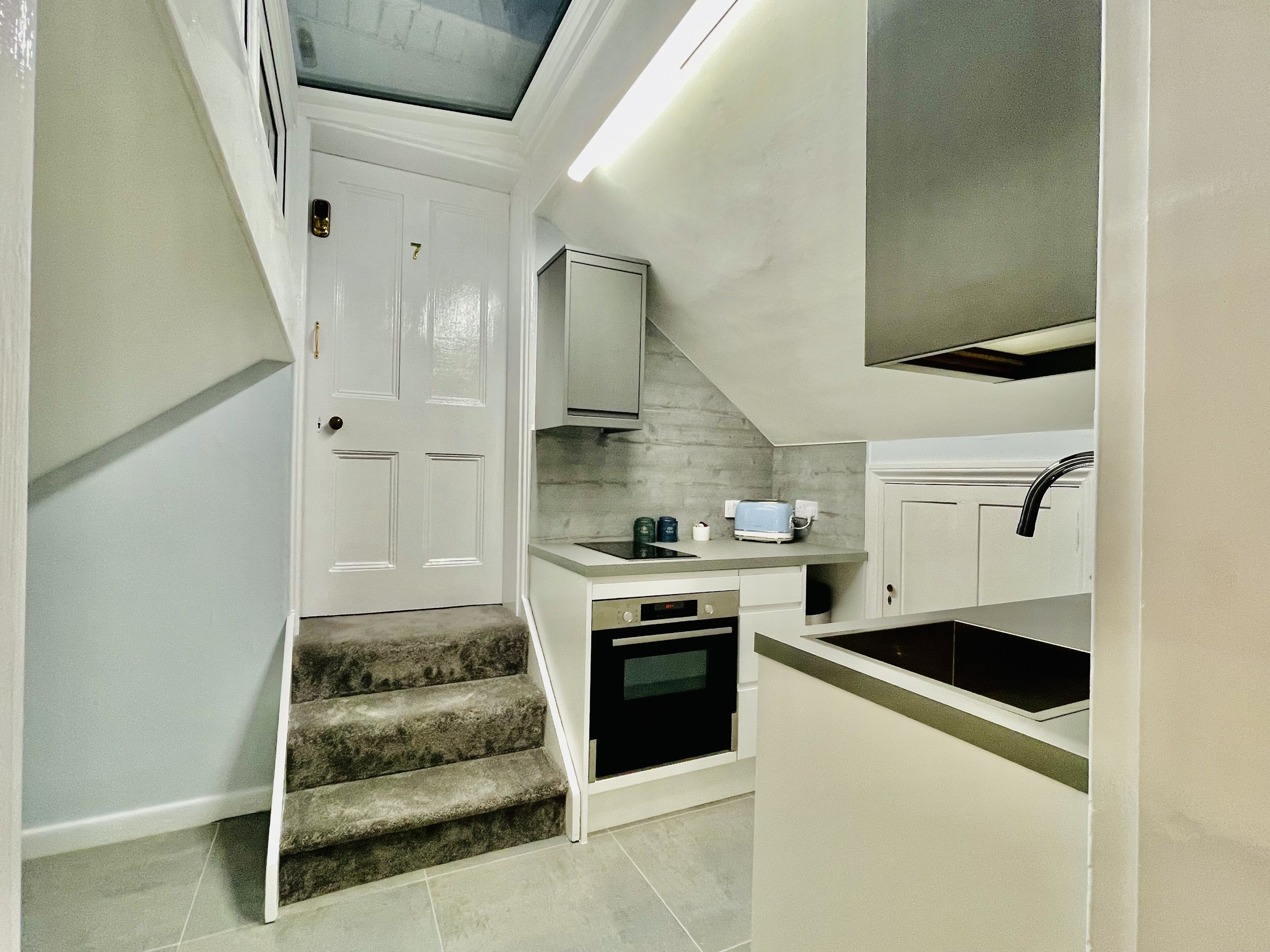 Una cocina compacta con horno integrado, una pequeña encimera y un lavabo.