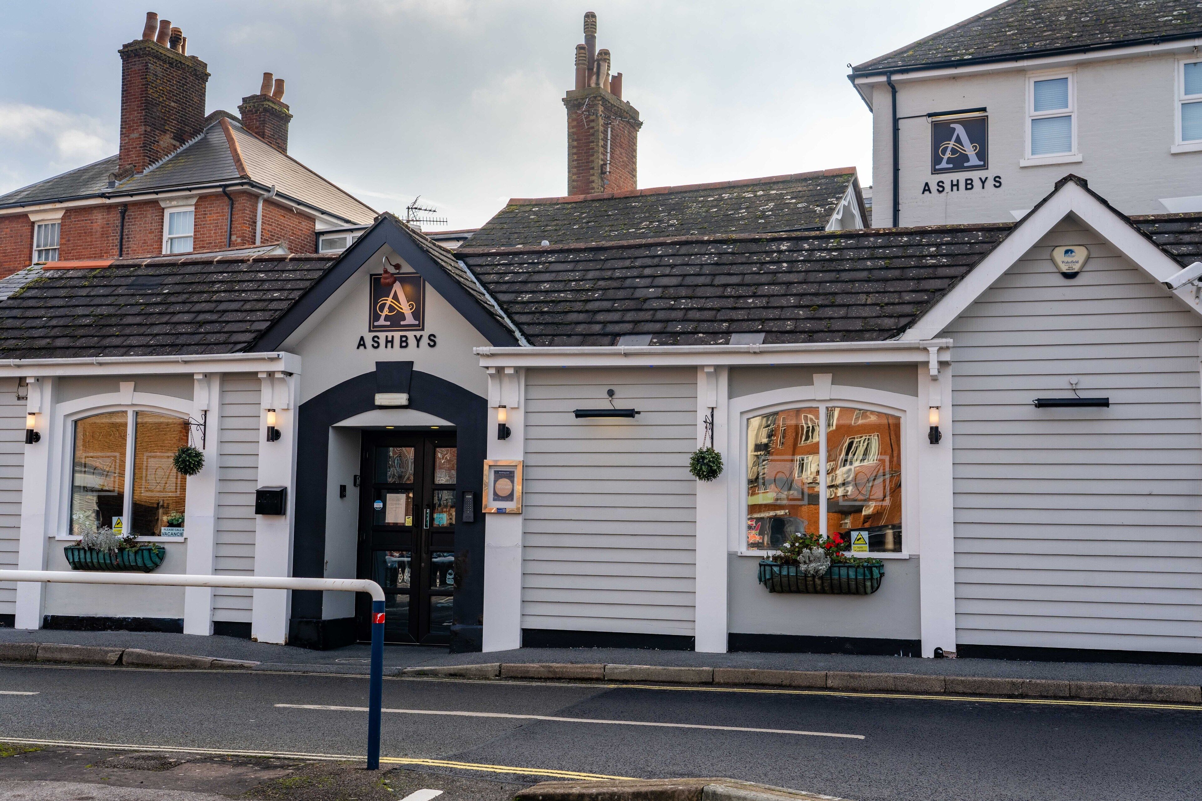 Un bâtiment avec une porte d’entrée noire et une enseigne sur laquelle on peut lire « ASHBYS ».