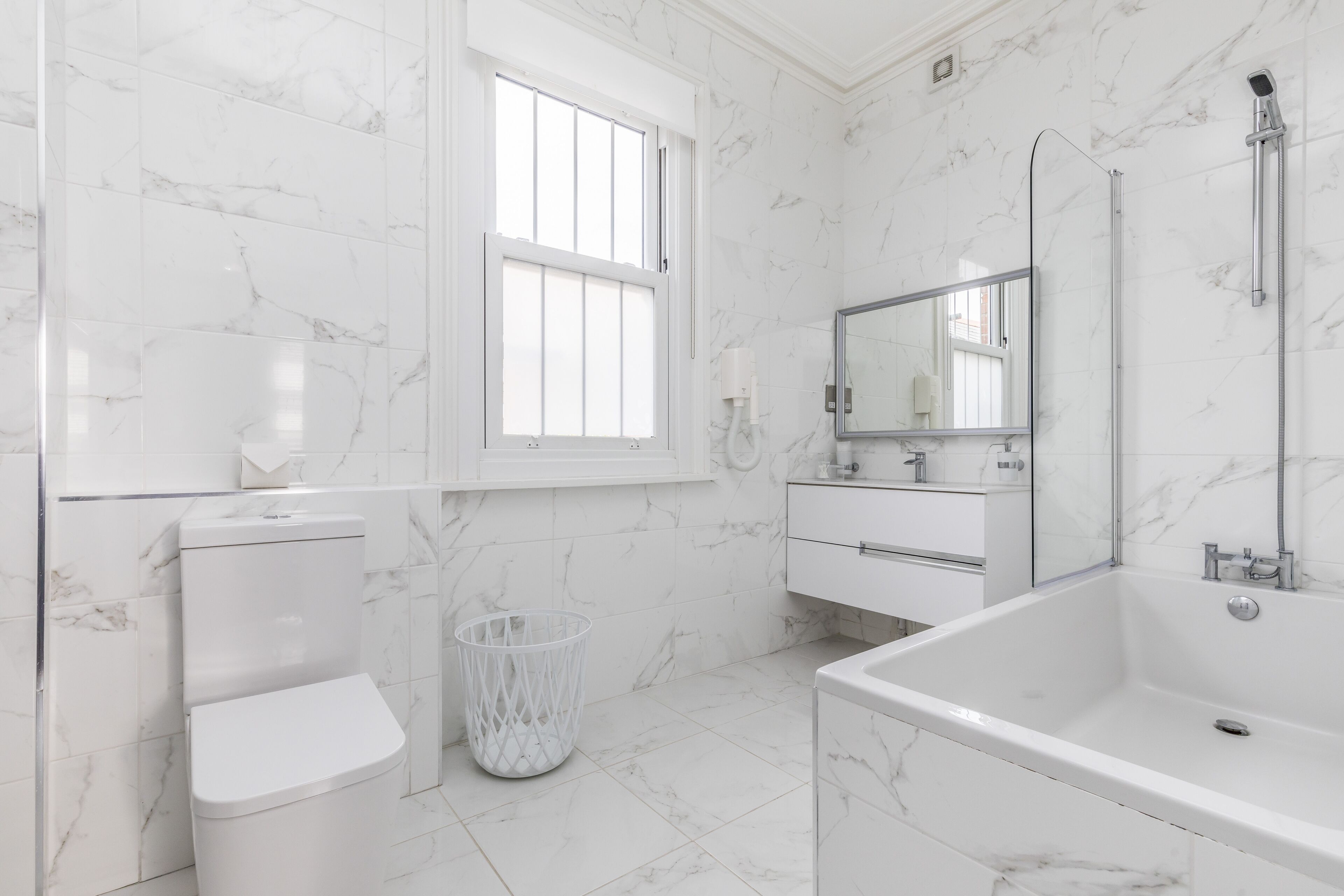 A modern bathroom with a toilet, bidet, and bathtub, all in white.