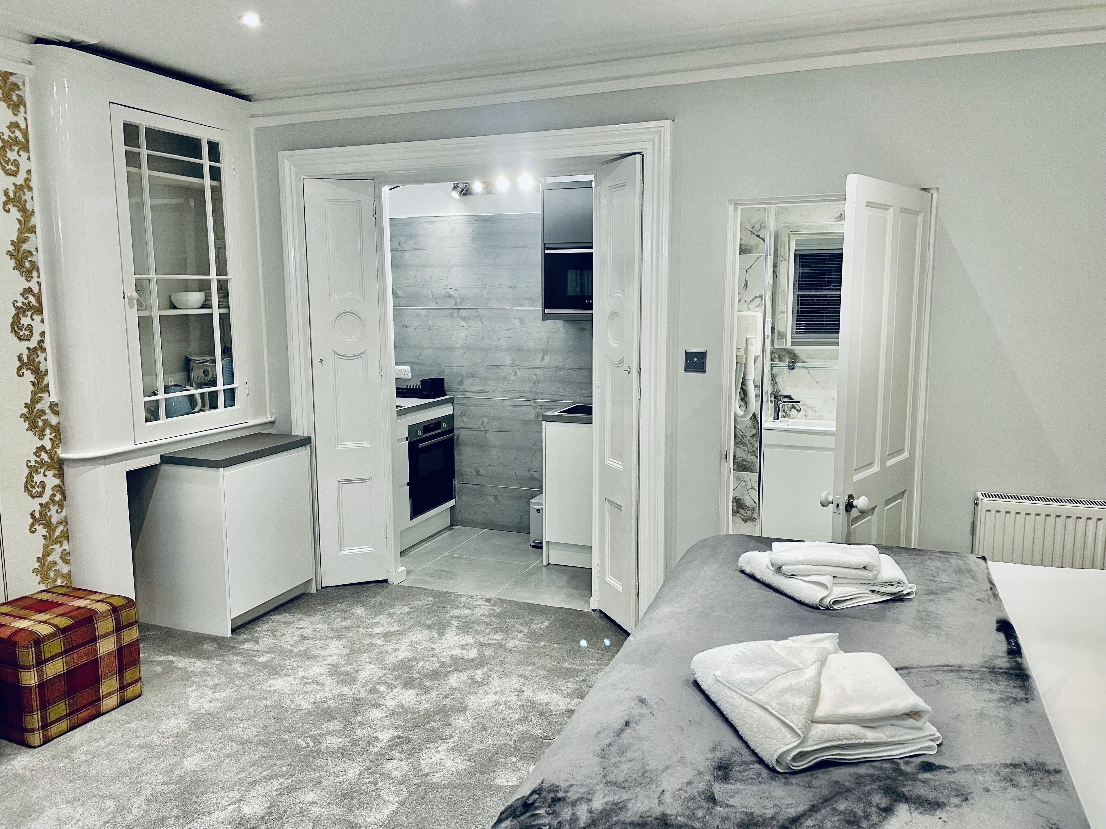 Habitación de hotel compacta con kitchenette, baño y una pequeña zona de estar con toallas.