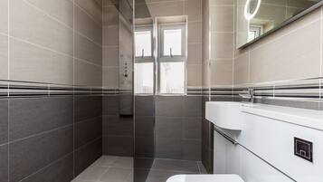 Ein modernes Badezimmer mit Duschkabine aus Glas, einem weißen Waschbecken und einem Spiegel mit Beleuchtung.
