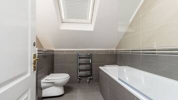 A modern bathroom with a skylight, a toilet, a bathtub, and a towel rack.