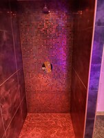 Una ducha con pared de mosaicos y desagüe circular.