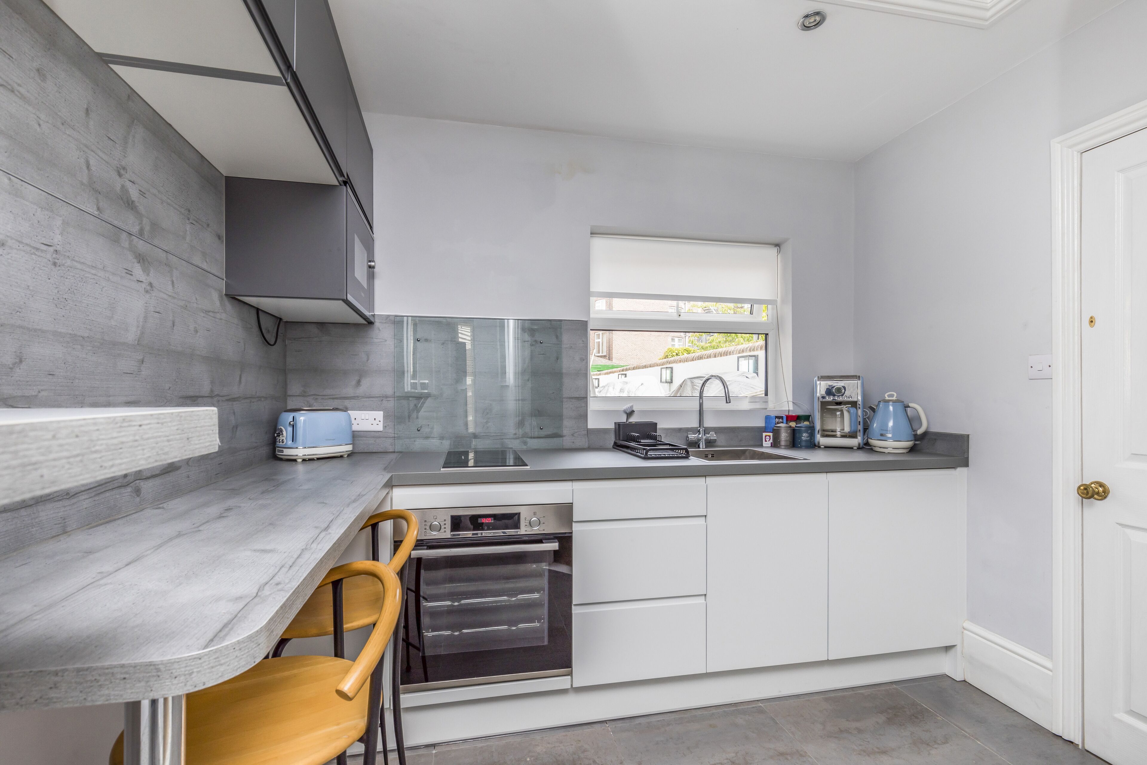 A modern kitchen with a built-in oven, a coffee maker, and a window providing natural light.