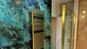 A bathroom with a teal marble wall, a gold-framed shower, and a white door. - Ashbys (Portsmouth)
