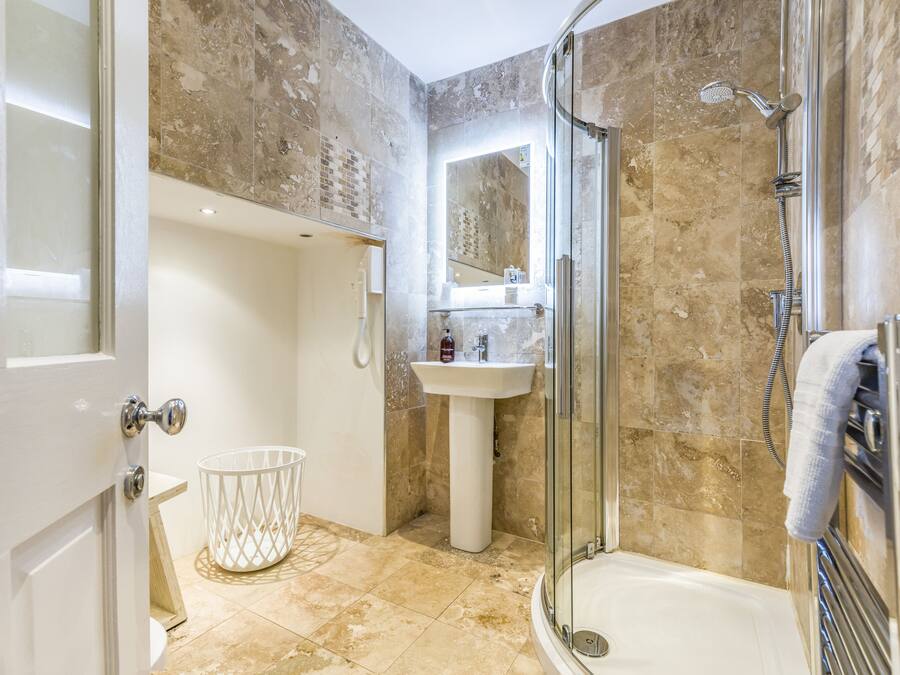 A modern bathroom with a glass shower enclosure, a pedestal sink, and a large mirror above the sink.