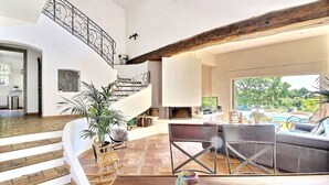 Un espacio habitable amplio con una escalera, una chimenea y vistas al exterior.