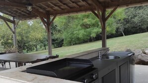 An outdoor kitchen with a stone countertop, a sink, and a grill.