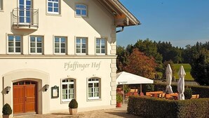 A building with a sign 'Paffinger Hof' and outdoor seating with umbrellas.