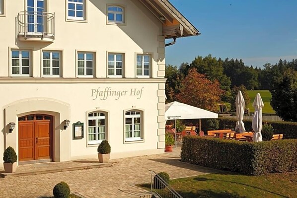 A building with a sign 'Paffinger Hof' and outdoor seating with umbrellas.