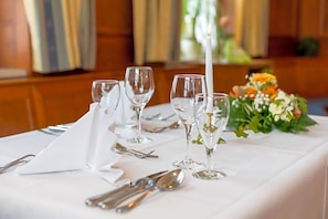 A table set for a meal with clear glassware and cutlery, a white napkin, and a floral centerpiece.