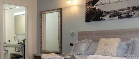 A bedroom with a large bed, a mirror, and a painting on the wall.