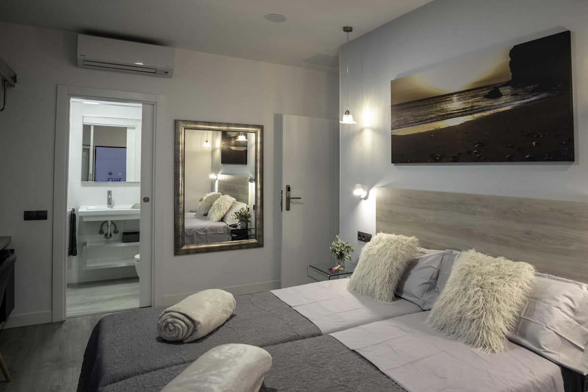 Une chambre moderne avec un grand lit, un miroir et un tableau accroché au mur.