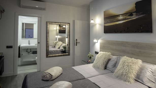 Ein modernes Schlafzimmer mit einem großen Bett, einem Spiegel und einem Gemälde an der Wand.