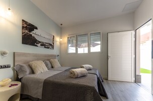 A bedroom with two beds, a large window, and a door leading to a balcony.